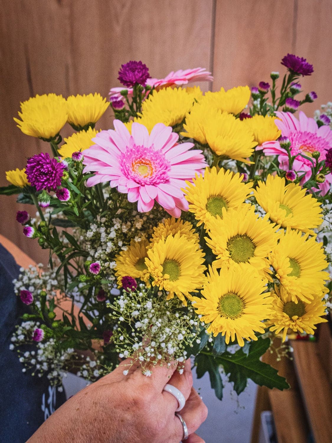 Kytice ze žlutých chryzantém a růžových gerber v ruce floristky, Květiny spolu